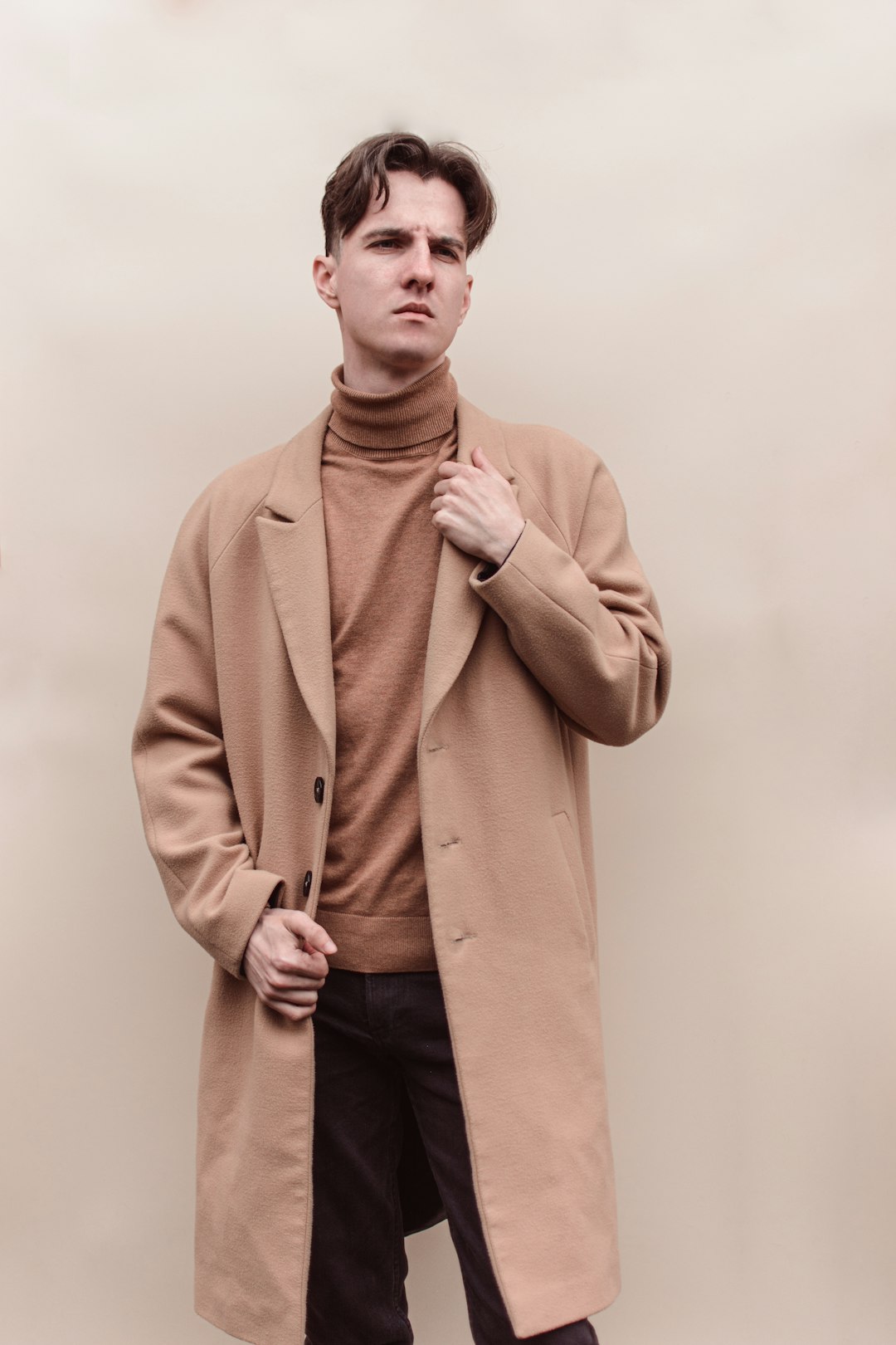 Man wearing a camel coat over a brown turtleneck