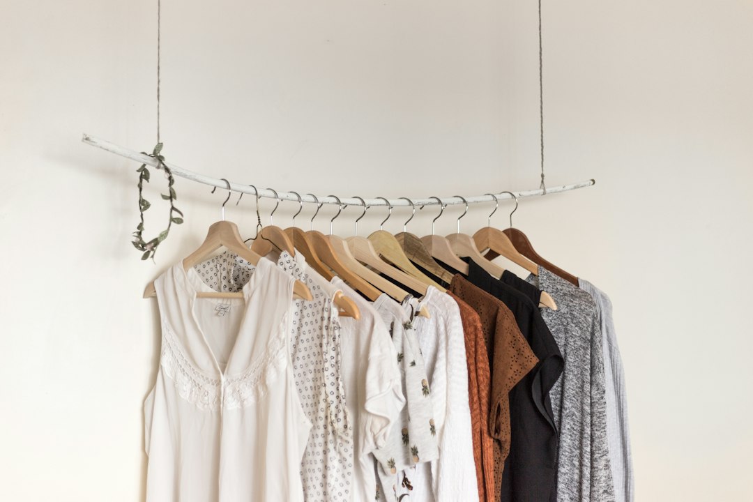 Neutral and warm-colored garments arranged on wooden hangers